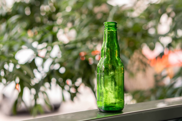 Zielona butelka z kroplami na zielonym naturalnym tle. - Zdjęcie, obraz