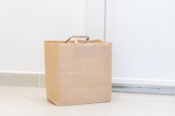 Het concept van contactloze levering tijdens de quarantaineperiode. Kraftpapieren tas met online aankoop. Milieuvriendelijk winkelen  - Foto, afbeelding