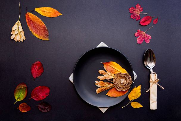 Černý talíř a příbory na podzim listí na černém pozadí.  - Fotografie, Obrázek