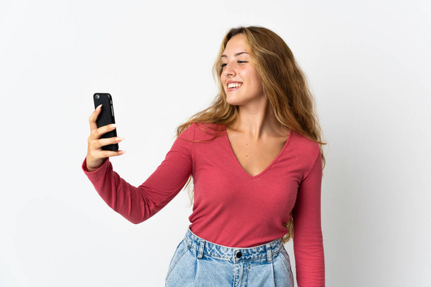 Mujer rubia joven aislada sobre fondo azul haciendo una selfie - Foto, Imagen