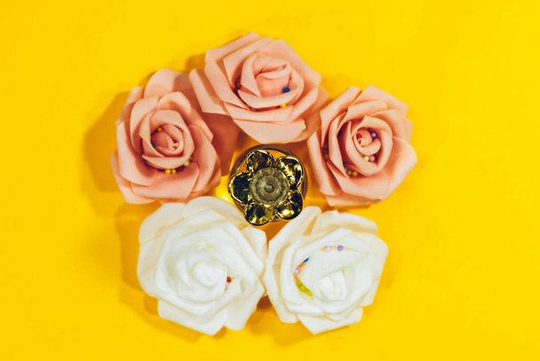 Vintage perfumy butelki z róż różowe kwiaty na żółtym tle - Zdjęcie, obraz