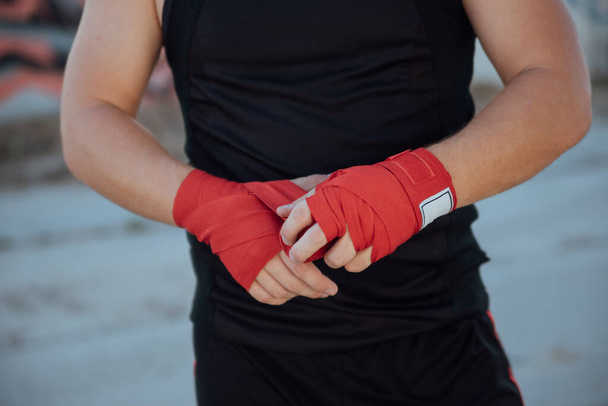 Closeup male hand of boxer with red boxing bandages.Boxing man binds the bandage on his hand, before training, detail photo - Foto, imagen
