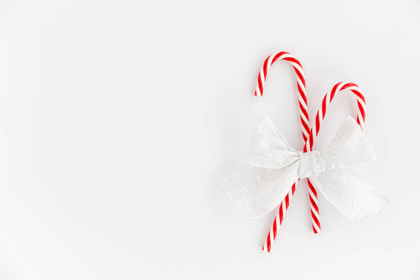 Christmas background of two red candy canes with festive bow isolated on white background. Top view. - Valokuva, kuva