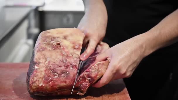 Rauwe biefstuk op een houten plank. Slachter snijdt rauw vlees met een mes in slow motion - Video