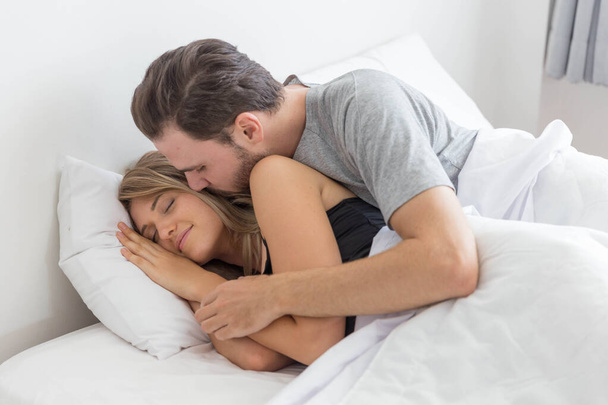 Кавказька пара цілується на ліжку в спальні
 - Фото, зображення