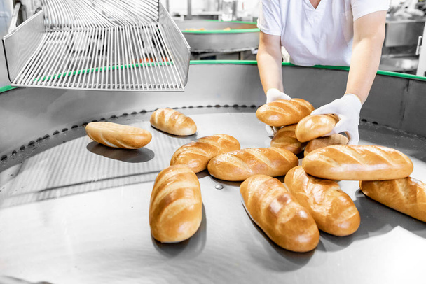 Baker werknemer verpakt brood te koop in de winkel, voedsel industriële productie - Foto, afbeelding