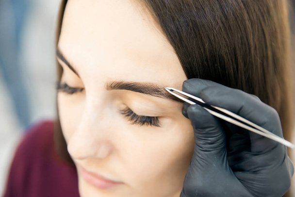 Brow correction master tweezers depilation of eyebrow hair in women - Φωτογραφία, εικόνα