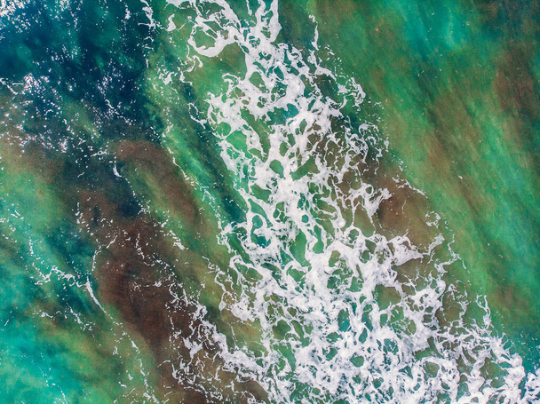 Small turquoise waves for surfing on shallows of sea low tide or ebb, aerial top view - Photo, Image