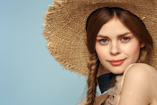 Girl in a straw hat portrait close-up pigtails fun red hair blue background - Foto, imagen