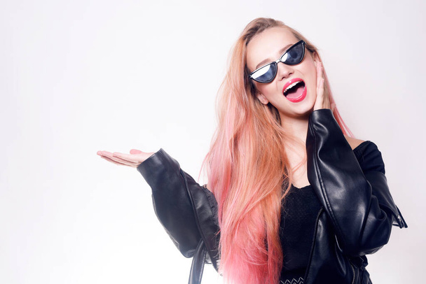 A girl with pink hair in glasses and black clothes shows an empty space for text or a product. Black Friday. Woman smiling - Photo, Image