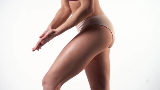 young woman in beige underwear applies moisturizer on leg - Footage, Video