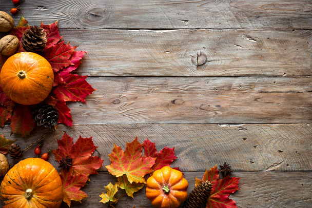 Autumn composition - pumpkins, autumn maple leaves, pine cones  on wooden background, creative flat lay, top view, copy space. Seasonal autumn Thanksgiving holiday concept. - Fotó, kép