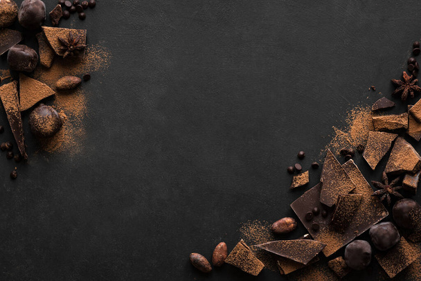 Kara Çikolata Arkaplanı. Çikolata parçaları, trüf mantarı, kakao tozu ve baharatlar siyah masada, üst manzara, boşluk kopyala. - Fotoğraf, Görsel