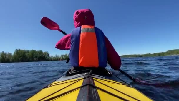 person rows sports kayak along lake water against blue sky - Footage, Video