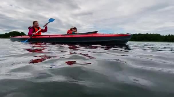 vrouw rijen sport kajak met dochter langs meer water - Video