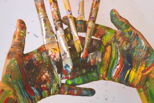Schilderborstels zijn op kleurrijke handen geschilderd - Foto, afbeelding