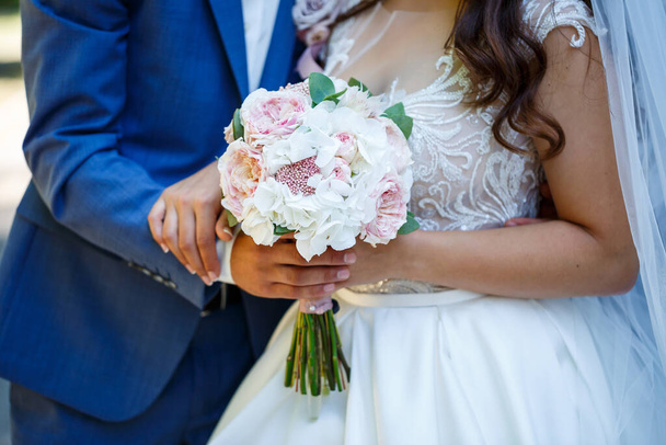 Piękny bukiet ślubny kwiatów w rękach nowożeńców - Zdjęcie, obraz