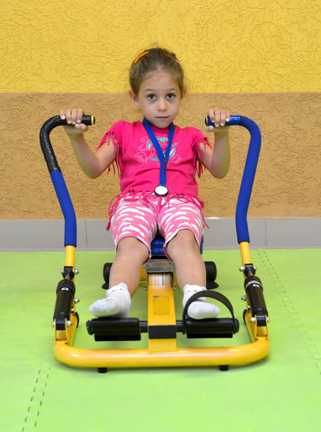 A little girl is engaged in a power simulator in a gym. Healthy lifestyle - Fotoğraf, Görsel