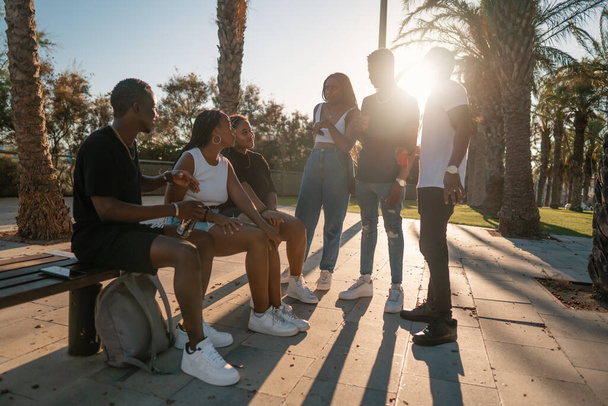 Grupo de jóvenes amigos negros africanos modernos felizmente sentados juntos - Foto, imagen