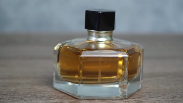 Tahta bir masanın üzerinde duran küçük bir şişe turuncu parfüm. - Video, Çekim