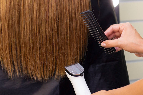 Hairdresser with a hair machine. cutting off split ends of hair with a clipper. close up. - Foto, imagen