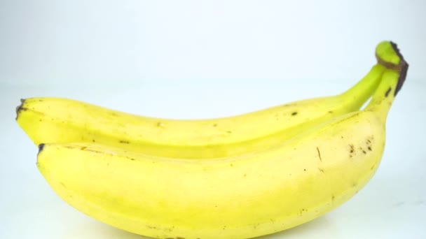 Két egész érett banán elszigetelt fehér alapon - Felvétel, videó