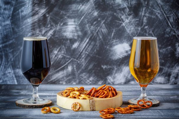 Salty snacks, pretzels and two glasses of dark and light beer. Negative space. Copy space. - Photo, Image