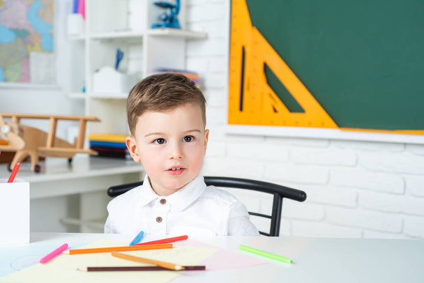 Elementary school kids in school. Cute child is sitting at a desk indoors. - Fotografie, Obrázek