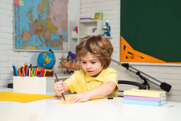 Happy cute industrious child is sitting at a desk indoors. Individual teaching. - Foto, imagen