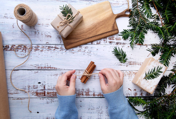 hands of a child making Christmas decoration on a table with fir branches - Foto, Imagen