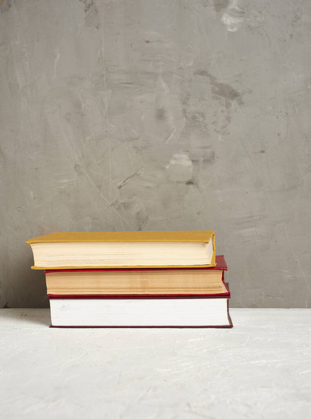 Stapel verschiedener gebundener Bücher auf grauem Hintergrund, Platz für Text, zurück zur Schule - Foto, Bild