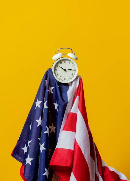 USA flag and alarm clock on yellow background  - Zdjęcie, obraz