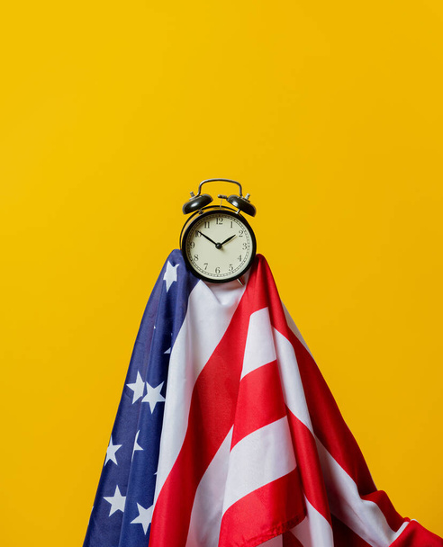 Amerikai zászló és ébresztőóra sárga háttérrel - Fotó, kép