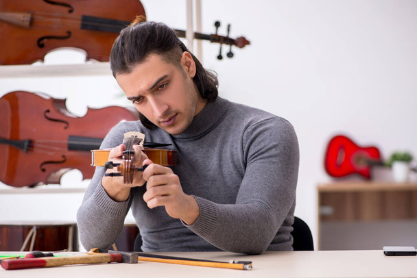 Молодий чоловік ремонтує скрипку
 - Фото, зображення