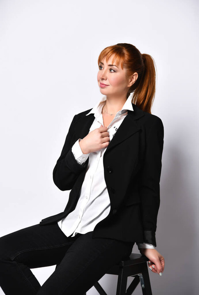 Young businesswoman sitting on chair against wall - Fotó, kép