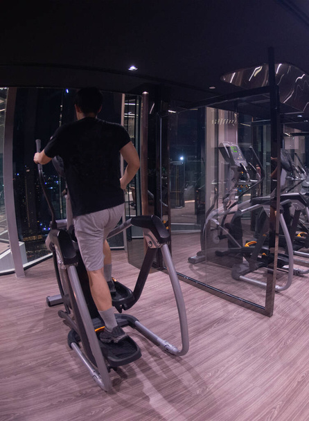 Young male are exercising by spinning the bike in the gym. Concept of healthy male with exercise. Asian young male playing exercise machines in the gym.  - Zdjęcie, obraz
