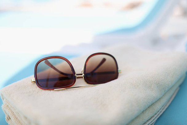 Sunglasses lie on towel on beach - Foto, afbeelding