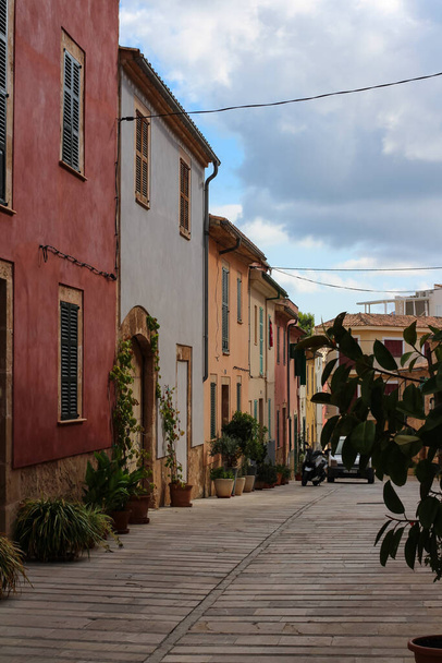 Una calle pavimentada con casas coloridas y flores en macetas a lo largo de las paredes. Mallorca. - Foto, Imagen