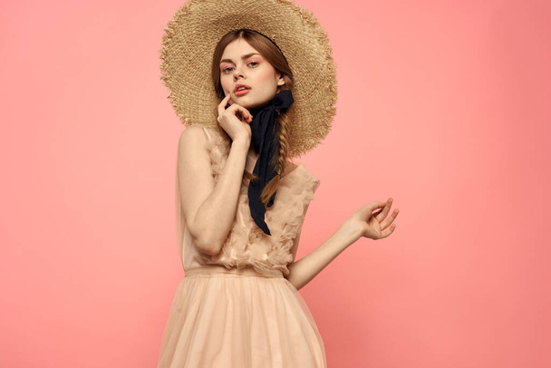 Fashionable woman in dress and hat with black ribbon on pink background cropped view of model emotions fun - Fotó, kép