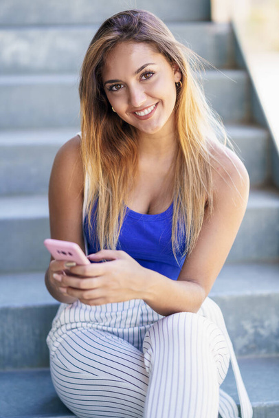 Chica usando un teléfono inteligente de pantalla táctil con ropa casual - Foto, Imagen