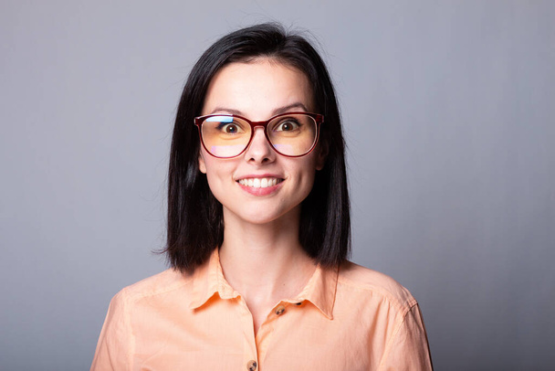 cute woman in glasses and orange shirt, gray background - Фото, зображення