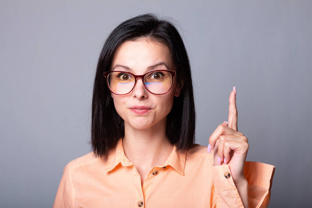 cute woman in glasses and orange shirt, gray background - 写真・画像
