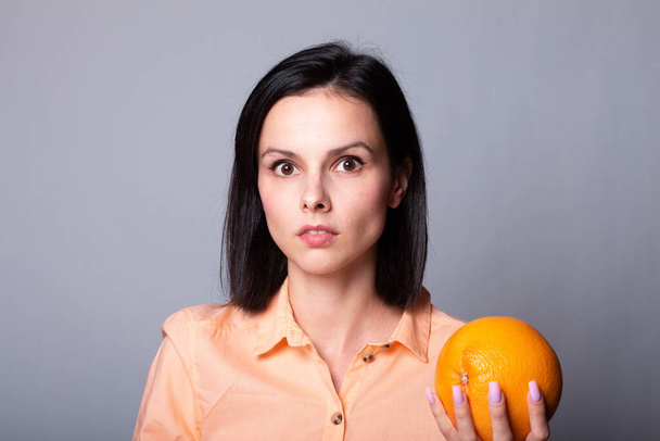woman in orange shirt holding grapefruit in her hands - Фото, изображение