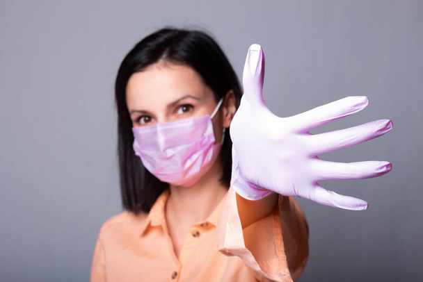 жінка в сорочці, медична маска і рукавички, сірий фон
 - Фото, зображення