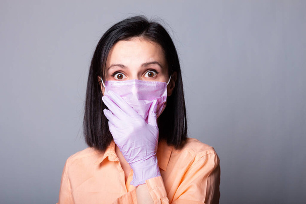 woman in shirt, medical mask and gloves, gray background - Fotó, kép
