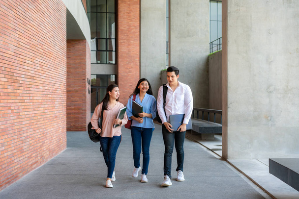 Azjaci trzej studenci spacerują i rozmawiają razem w sali uniwersyteckiej podczas przerwy na Uniwersytecie. Edukacja, Nauka, Student, Kampus, Uniwersytet, Koncepcja stylu życia - Zdjęcie, obraz