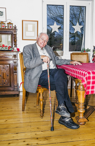 old Grandfather sitting with his walking stick at the table - Foto, Imagen
