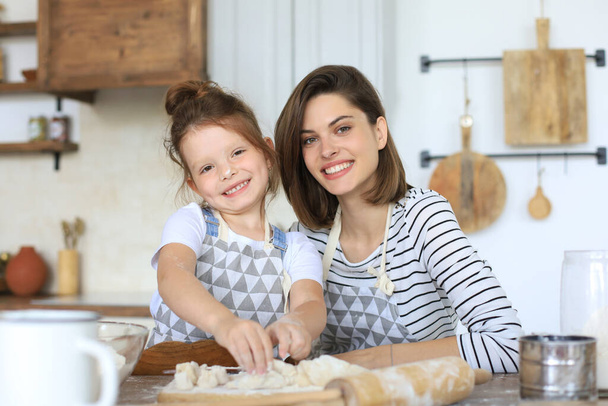 Playful little girl cooking at kitchen with her loving mother - Foto, Imagem