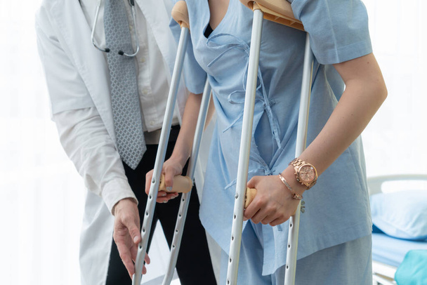 Doctor takes care of patient in crutch at hospital - Photo, Image