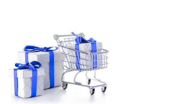 Xmas gift. Trolley cart for supermarket with christmas or birthday gift box isolated on white background. Creative idea for shopping online, xmas sale in supermarket - Photo, image